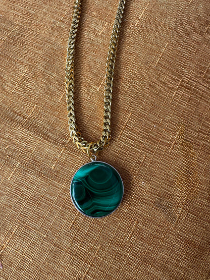 Necklace with a green pendant on a brown fabric background