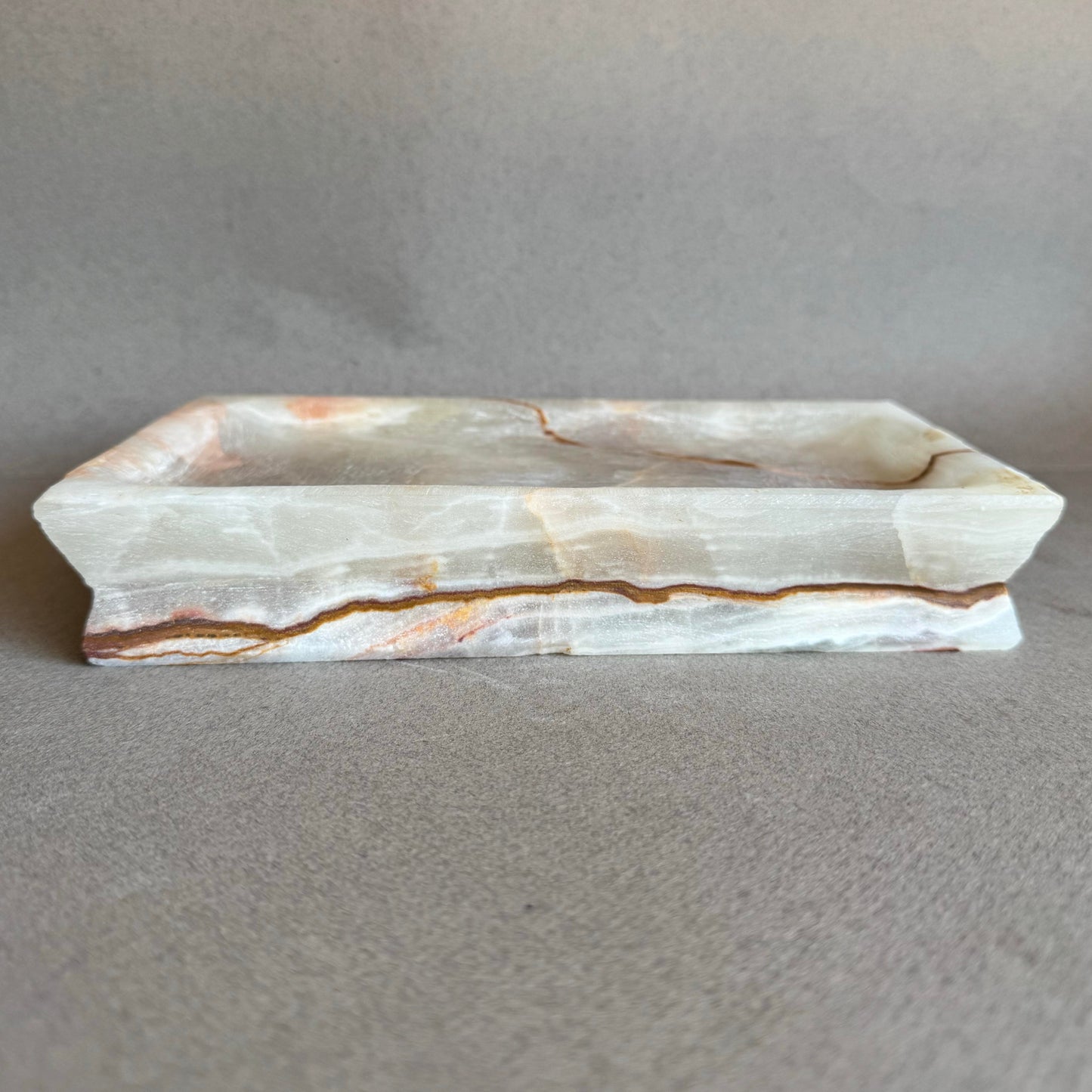  Natural stone vanity tray with warm rust, amber, and beige layers
