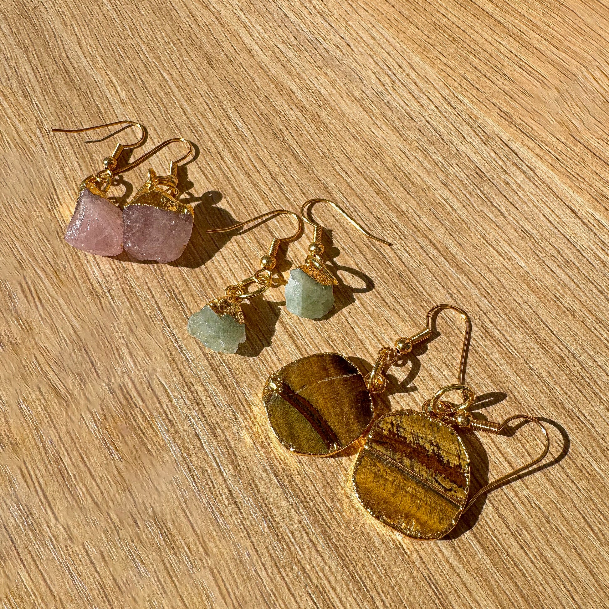 Gold earrings with gemstones on a wooden surface