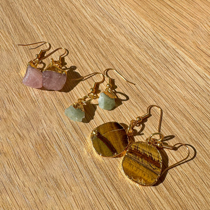 Gold earrings with gemstones on a wooden surface