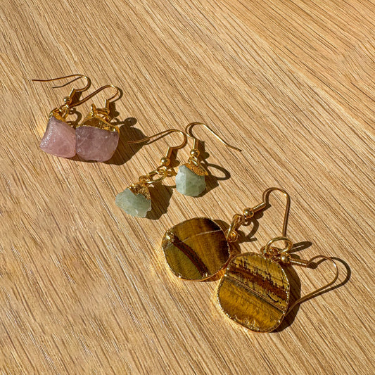 Gold earrings with gemstones on a wooden surface