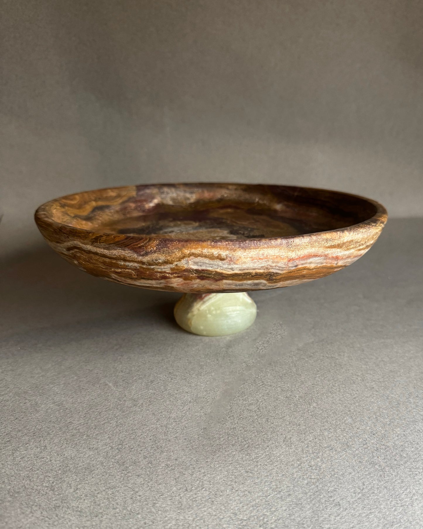 Decorative stone bowl with a small stone base on a gray surface
