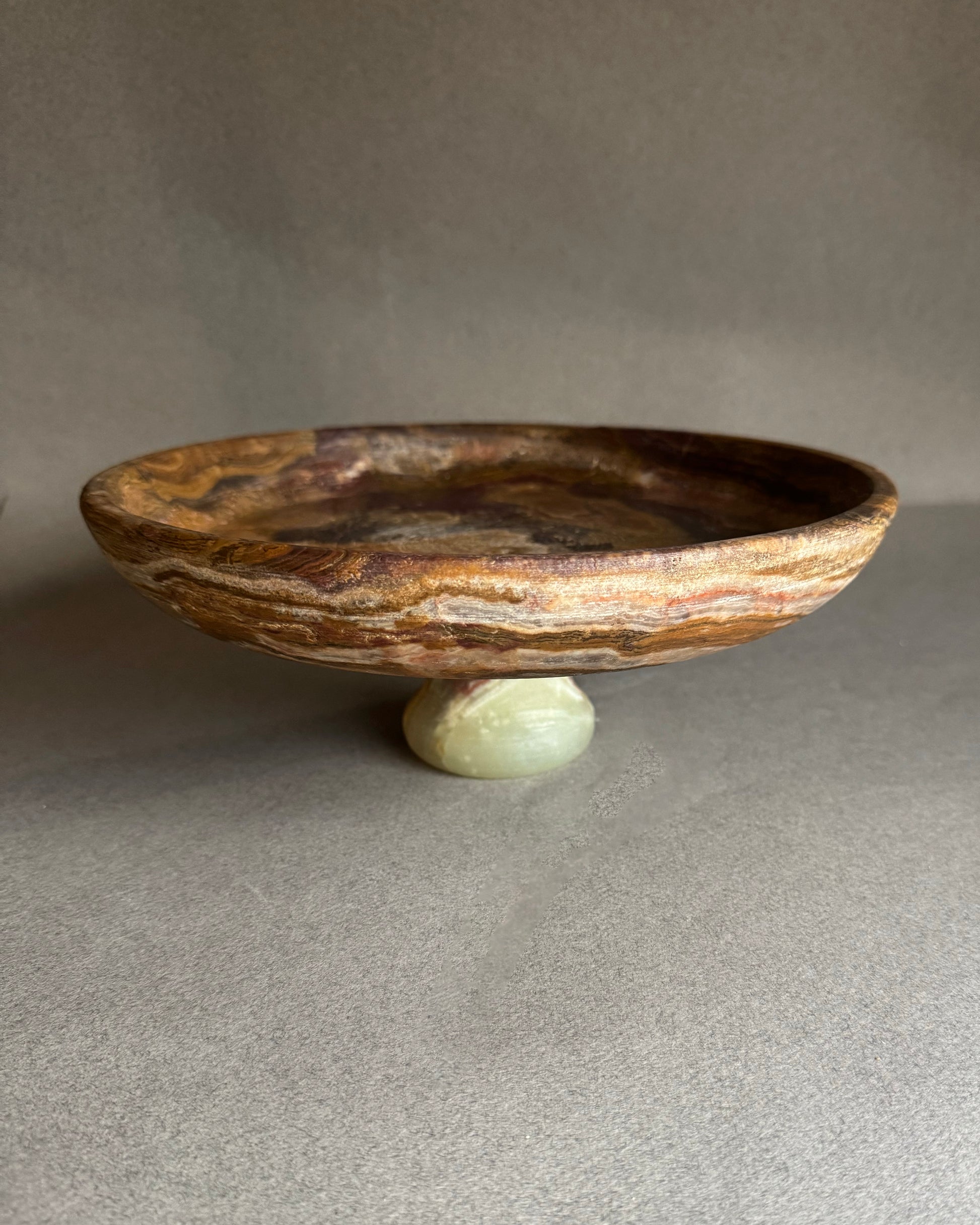 Decorative stone bowl with a small stone base on a gray surface