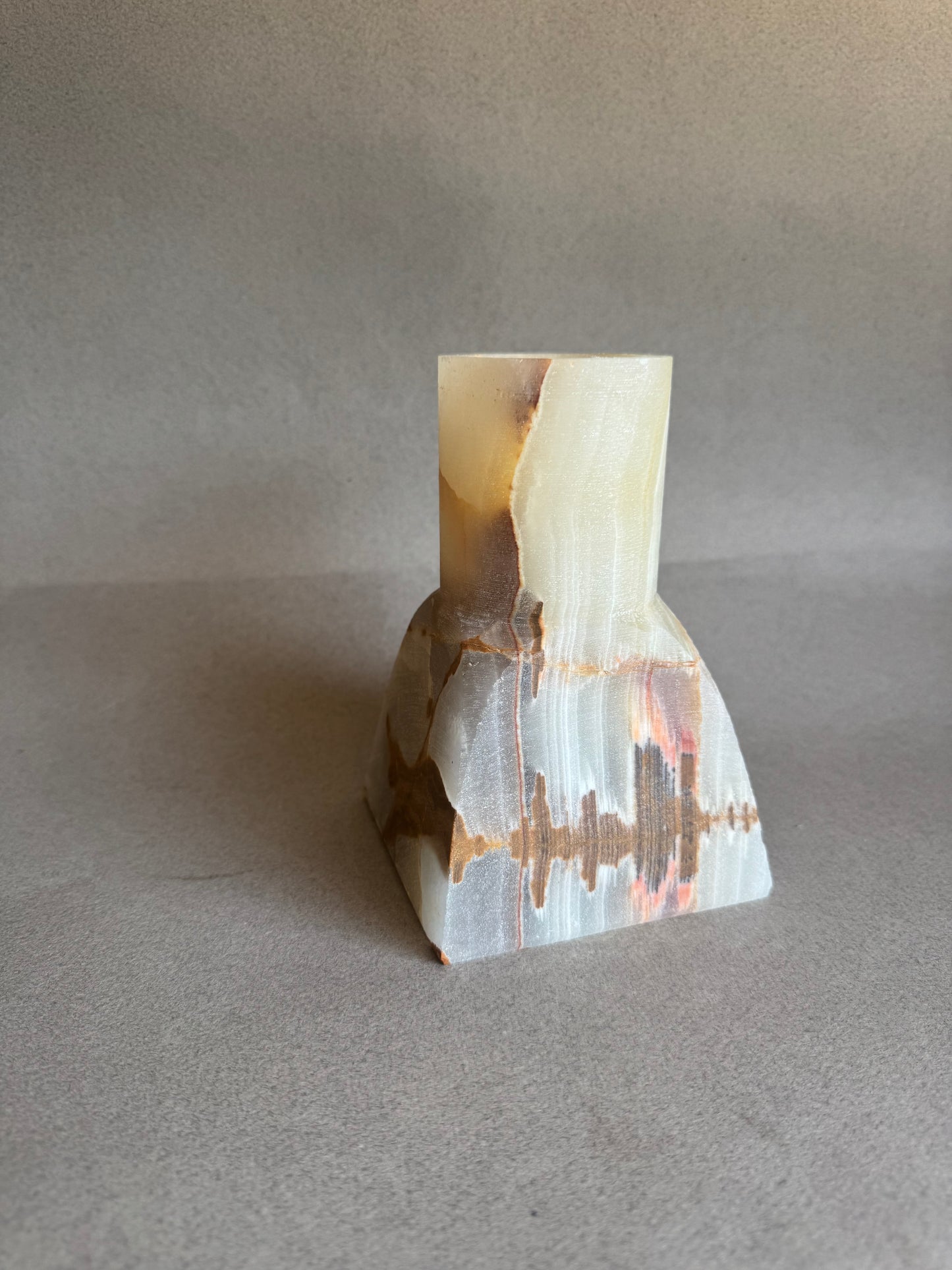 Polished stone vase with a geometric cut on a gray background