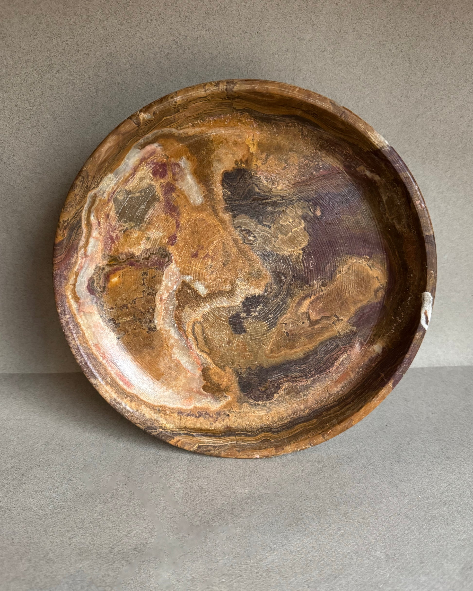 Decorative stone bowl with swirling brown and beige patterns on a gray background