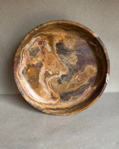 Decorative stone bowl with swirling brown and beige patterns on a gray background
