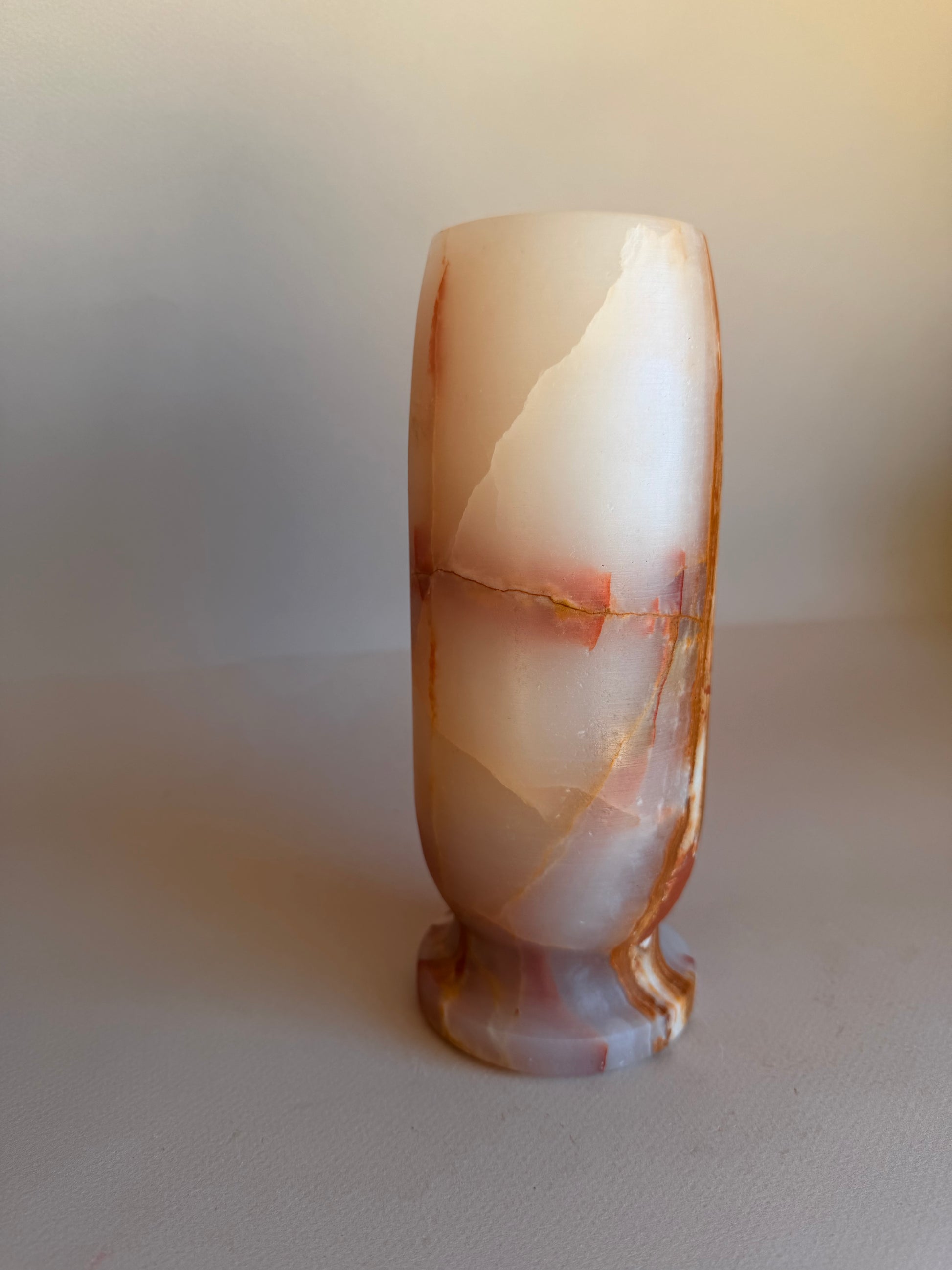 Polished stone onyx vase  with a marbled pattern on a plain background