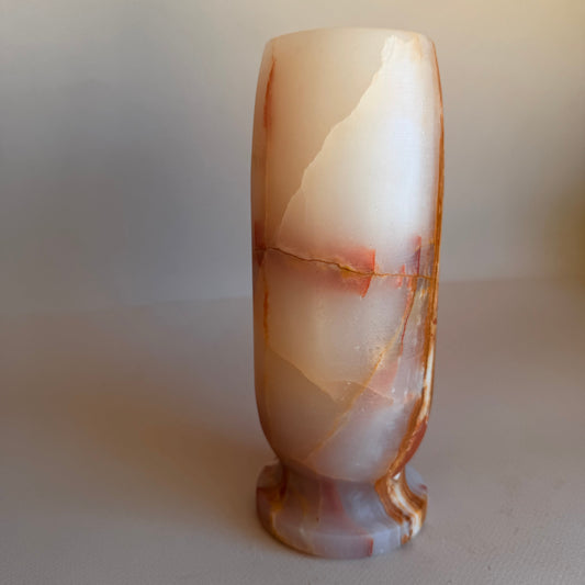 Polished stone onyx vase  with a marbled pattern on a plain background
