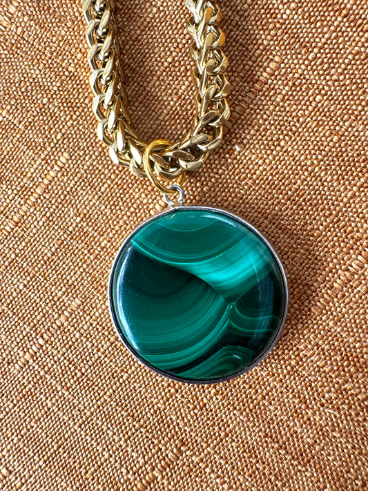Necklace with a green circle malachite pendant on a textured beige background