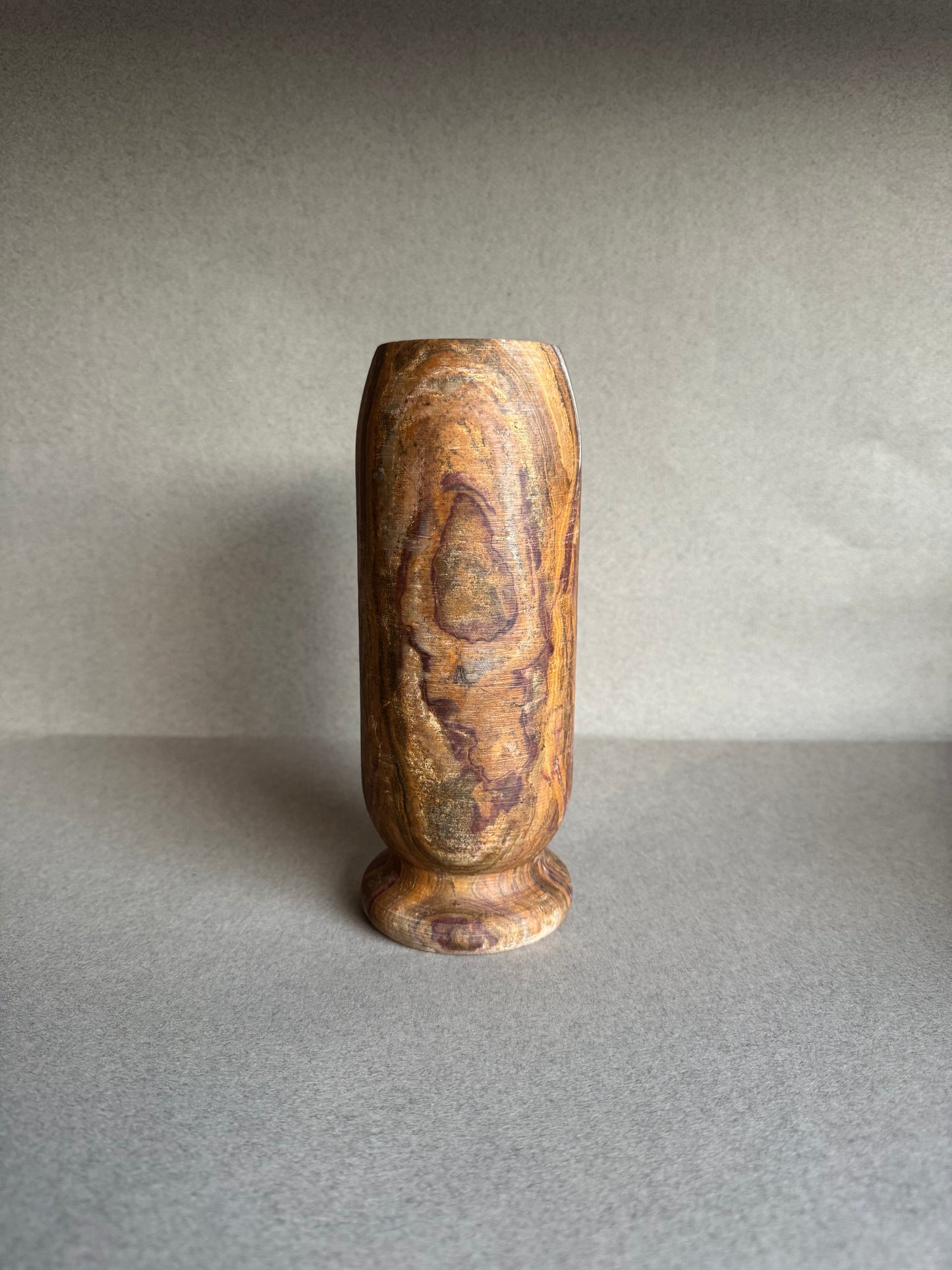 Earth-toned onyx vase with striated veining and rounded base