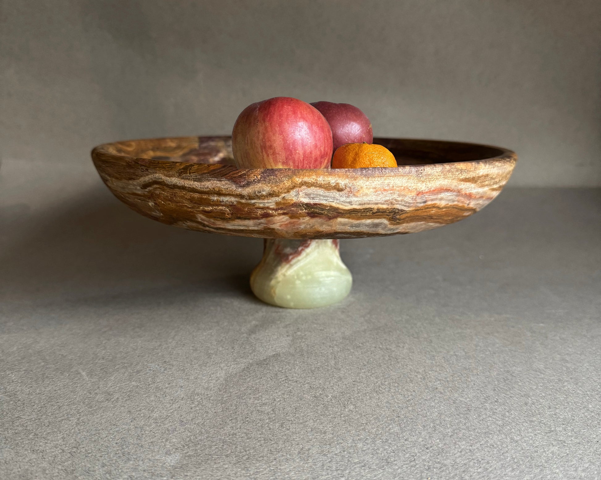 Decorative stone bowl with fruits on a neutral background