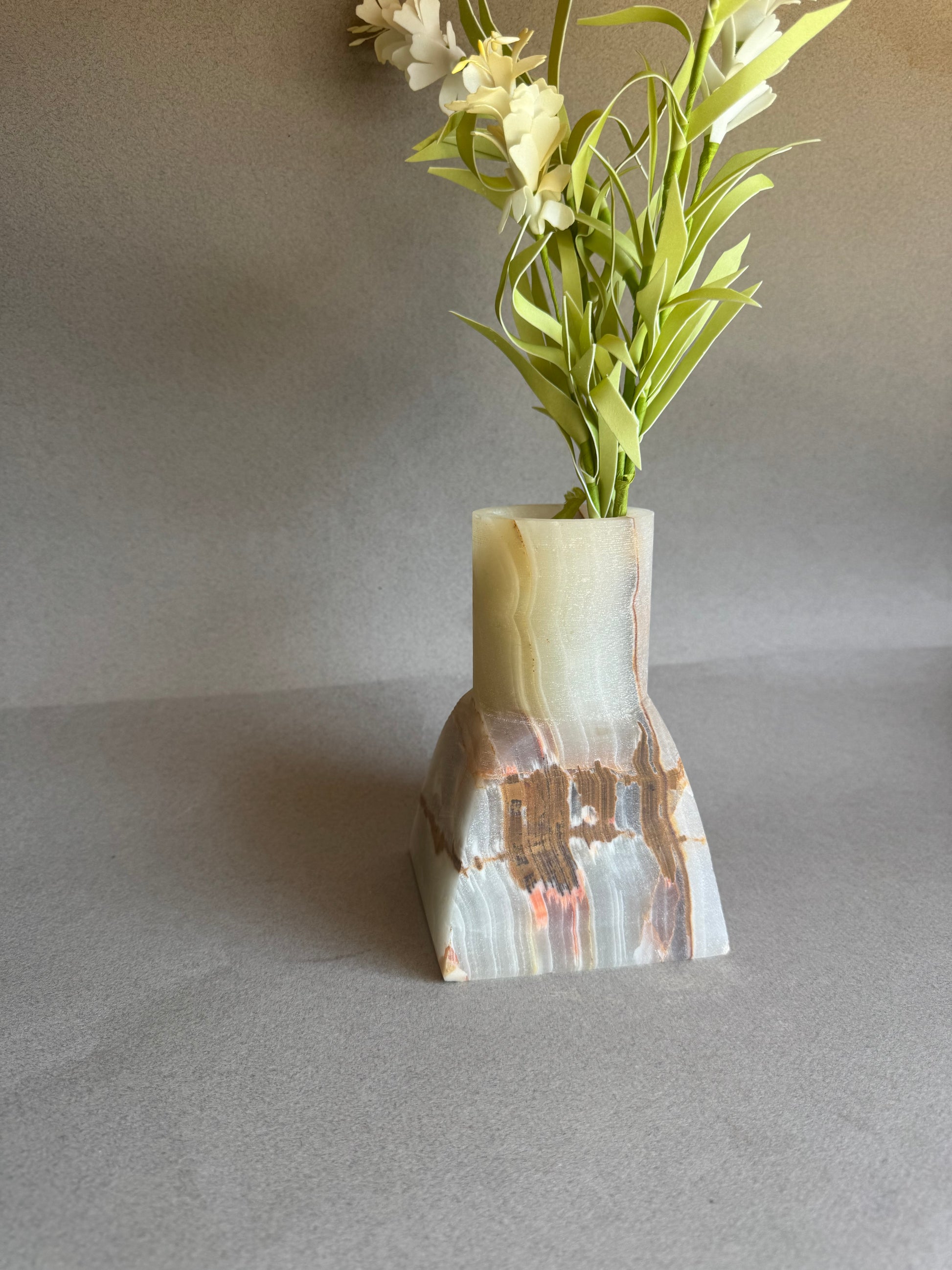 Decorative vase with a natural stone pattern holding greenery against a plain background