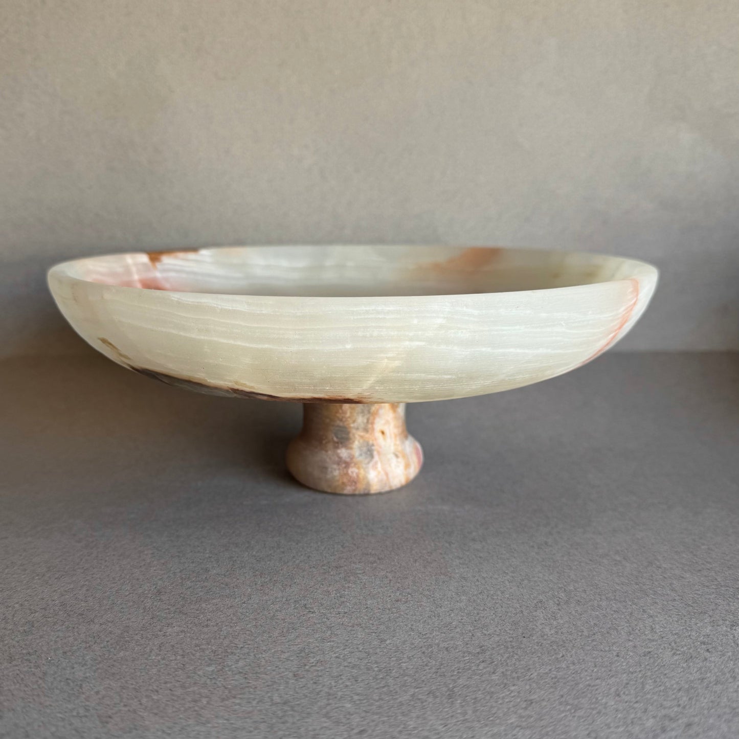 Onyx pedestal bowl glowing with natural light, showing depth and layered veining