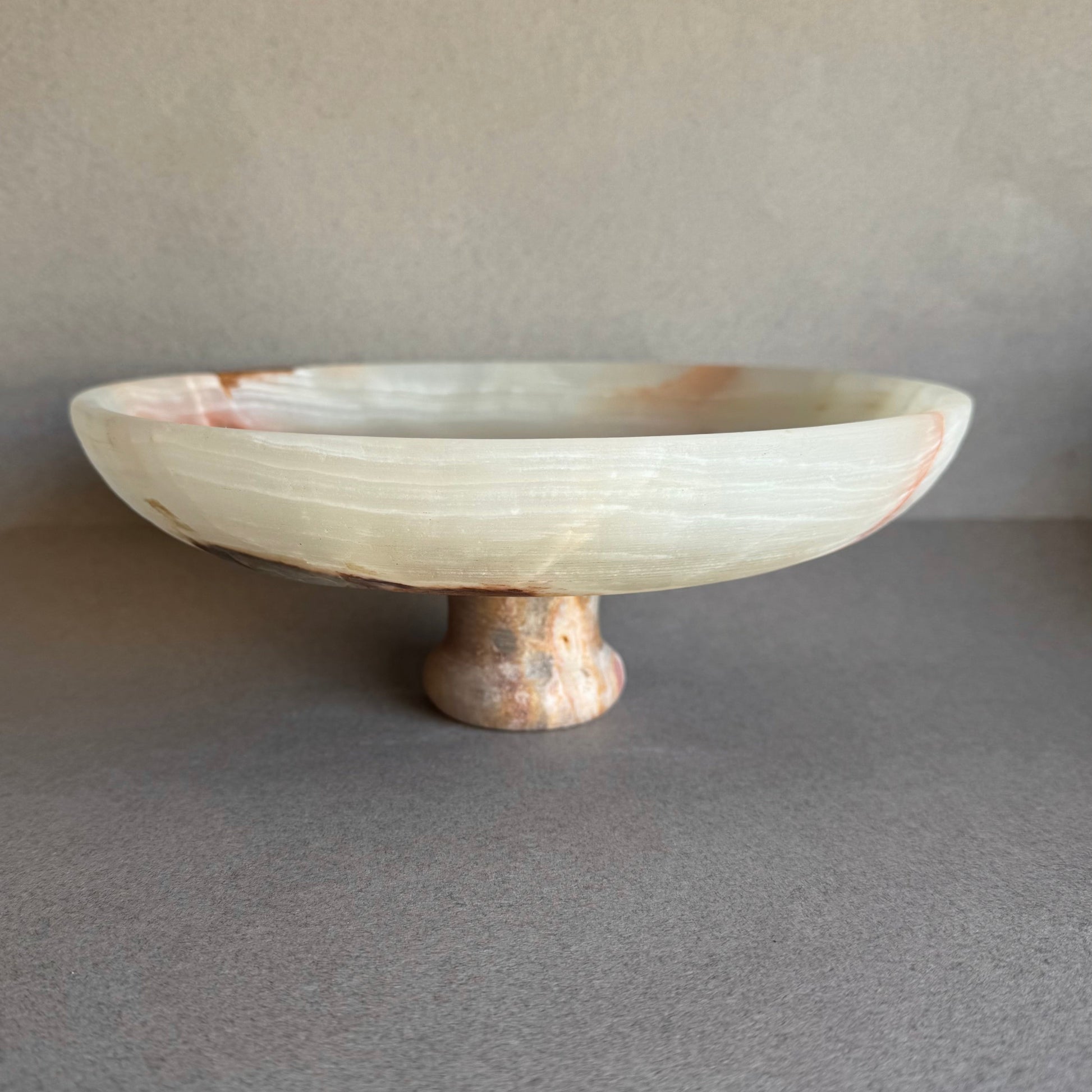 Onyx pedestal bowl glowing with natural light, showing depth and layered veining