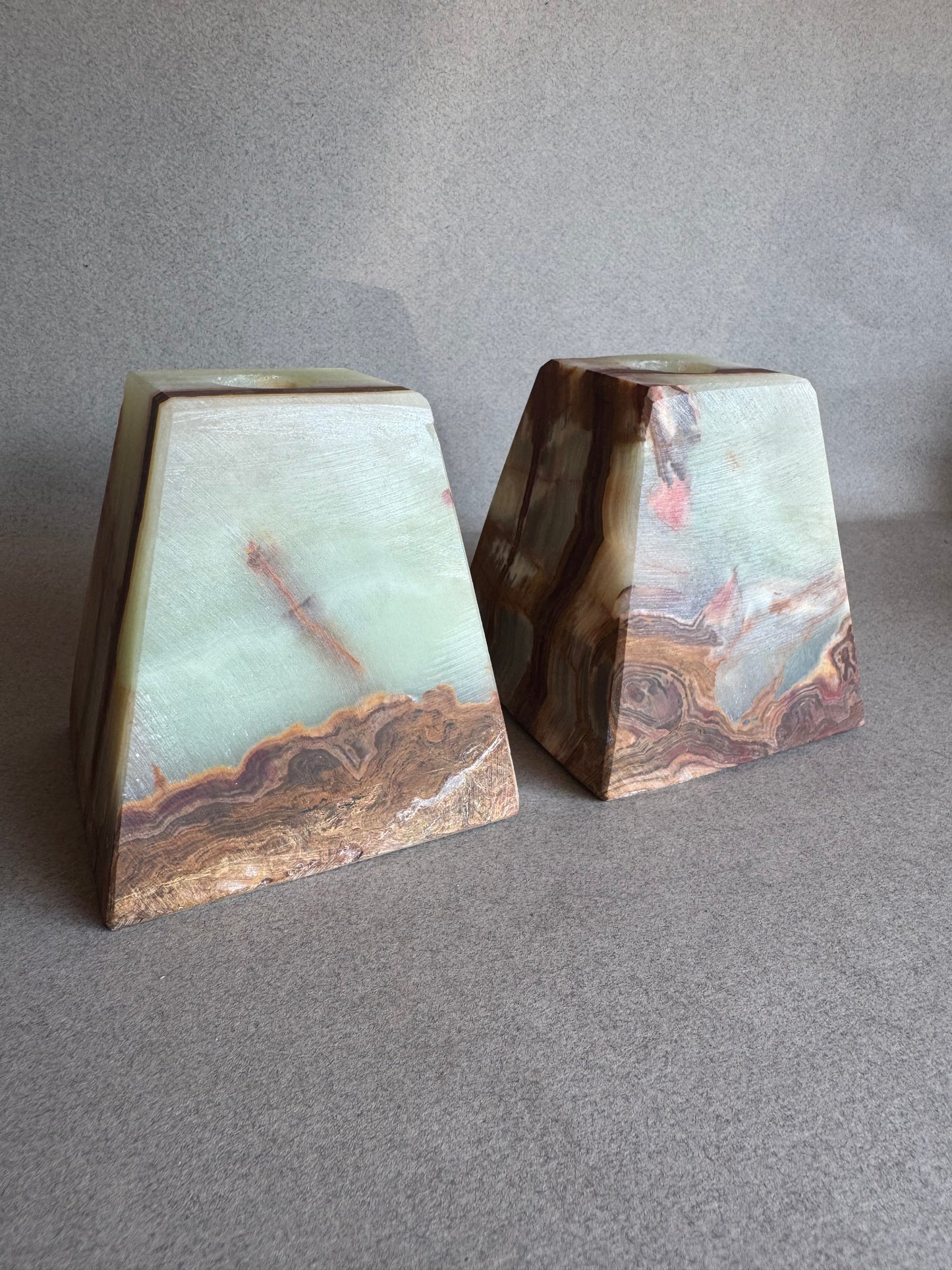 Two polished stone pieces with marbled patterns on a gray surface