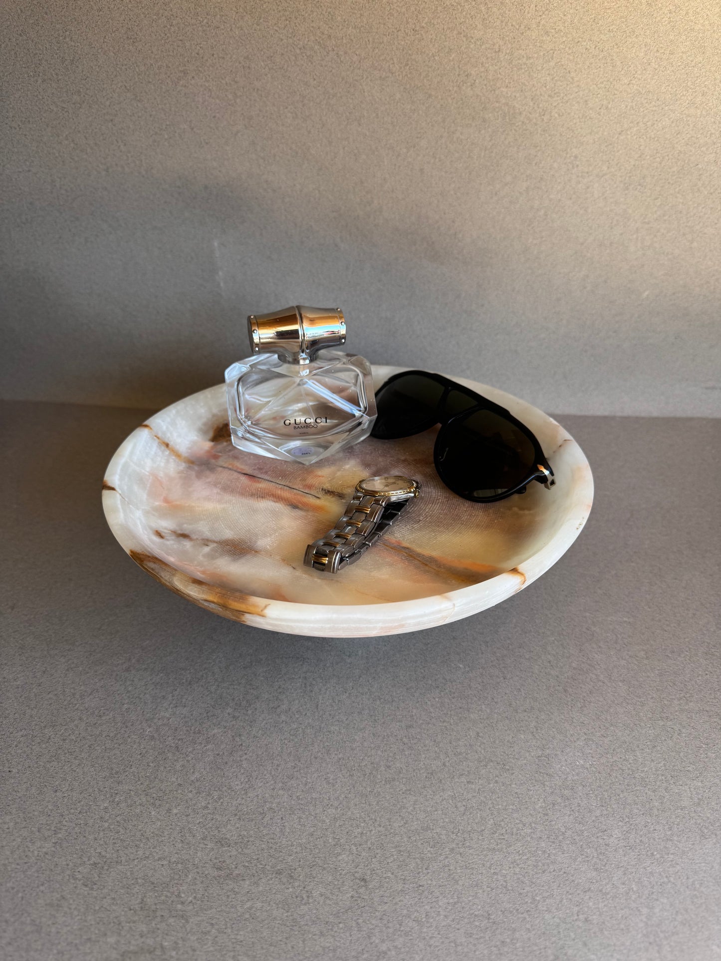 Onyx bowl styled with perfume, sunglasses, and jewelry — versatile gift idea