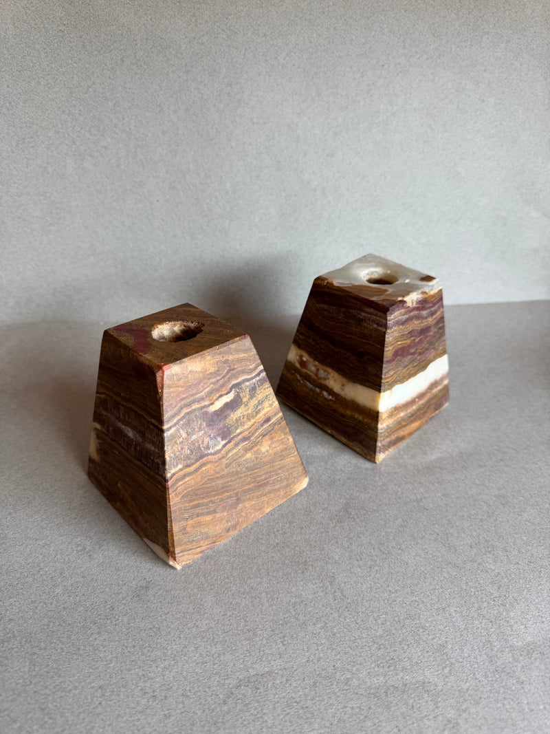 Two brown stone candle holders on a gray surface with a neutral background