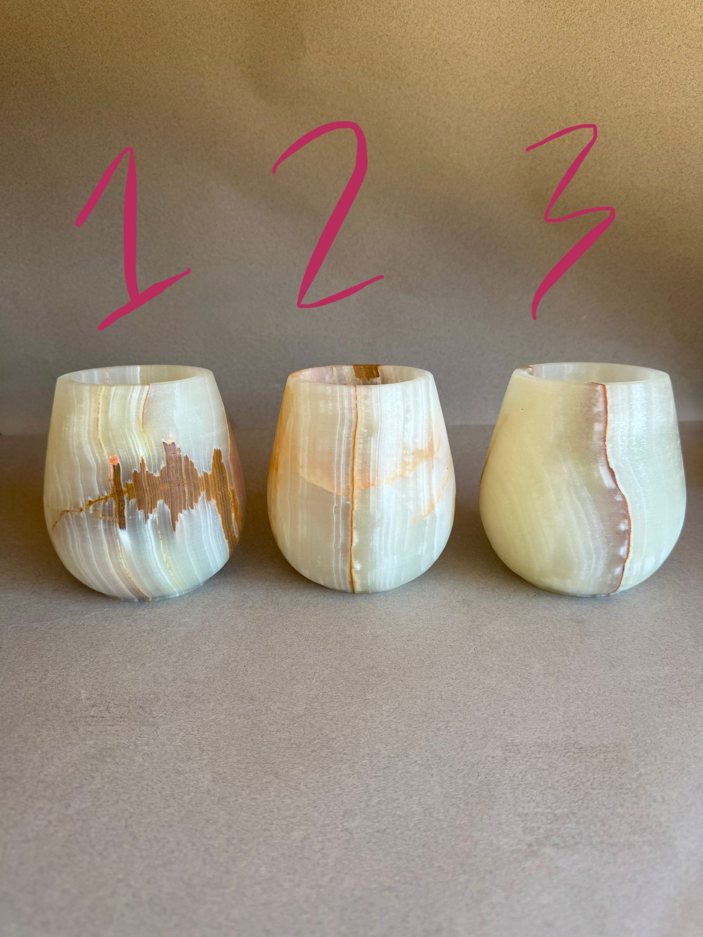 Three onyx tumblers with a light pattern on a beige background