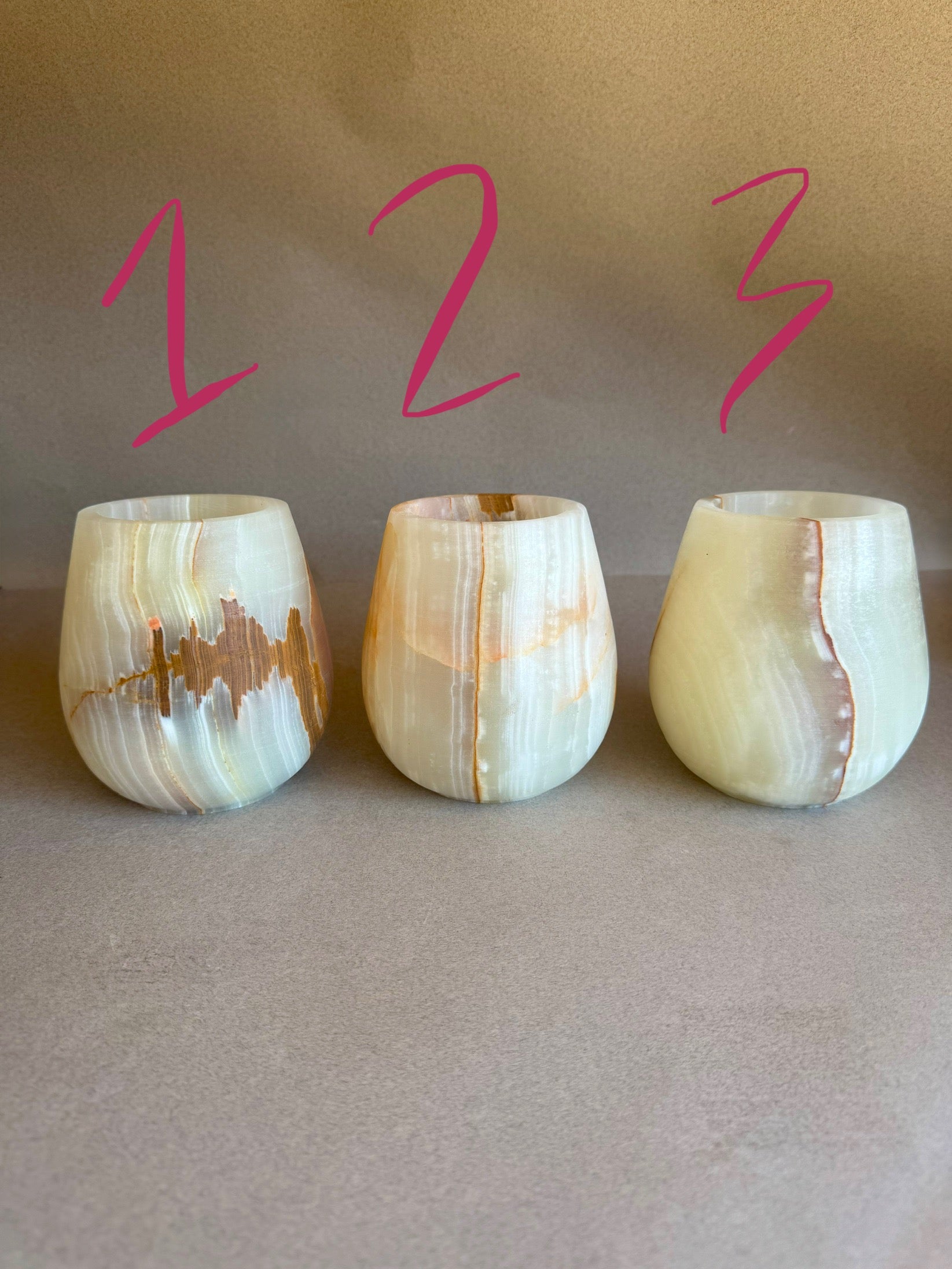 Three onyx tumblers with a light pattern on a beige background