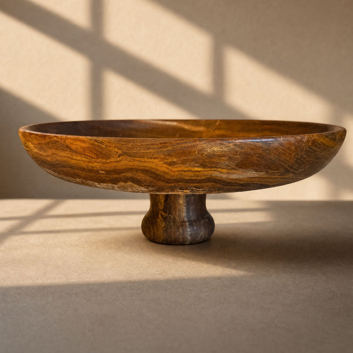 brown stone bowl with a pedestal base on a neutral background