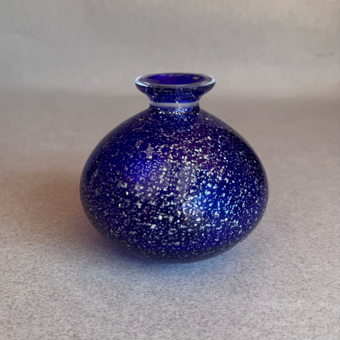 Blue speckled vase on a gray background