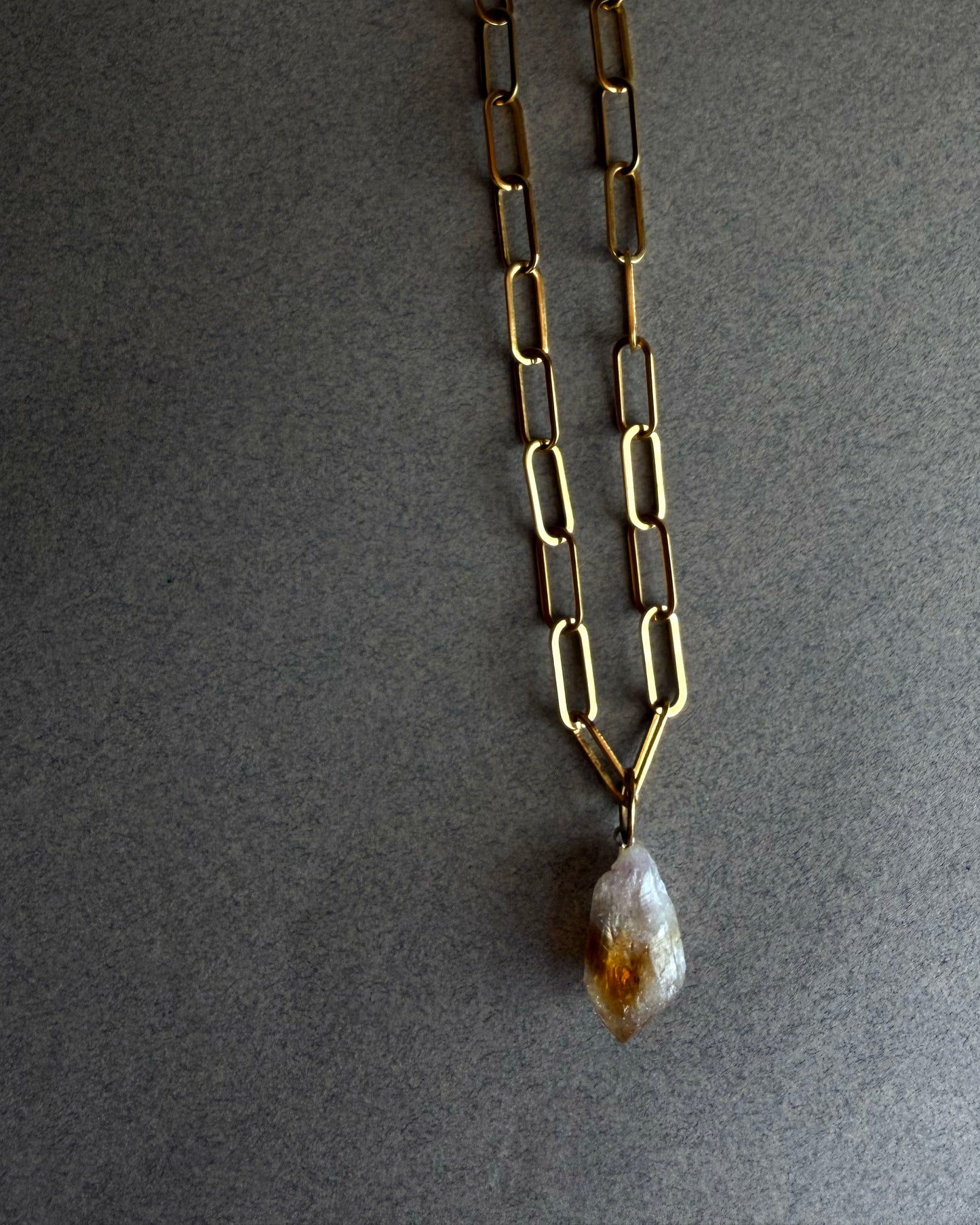 Raw citrine crystal necklace on gold paperclip chain, displayed on black sculptural bust, minimalist gemstone jewelry
