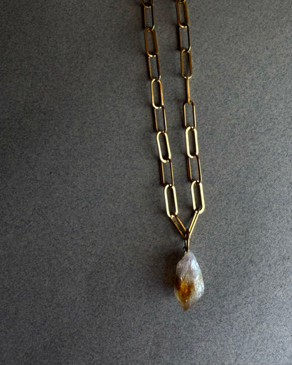 Raw citrine crystal necklace on gold paperclip chain, displayed on black sculptural bust, minimalist gemstone jewelry
