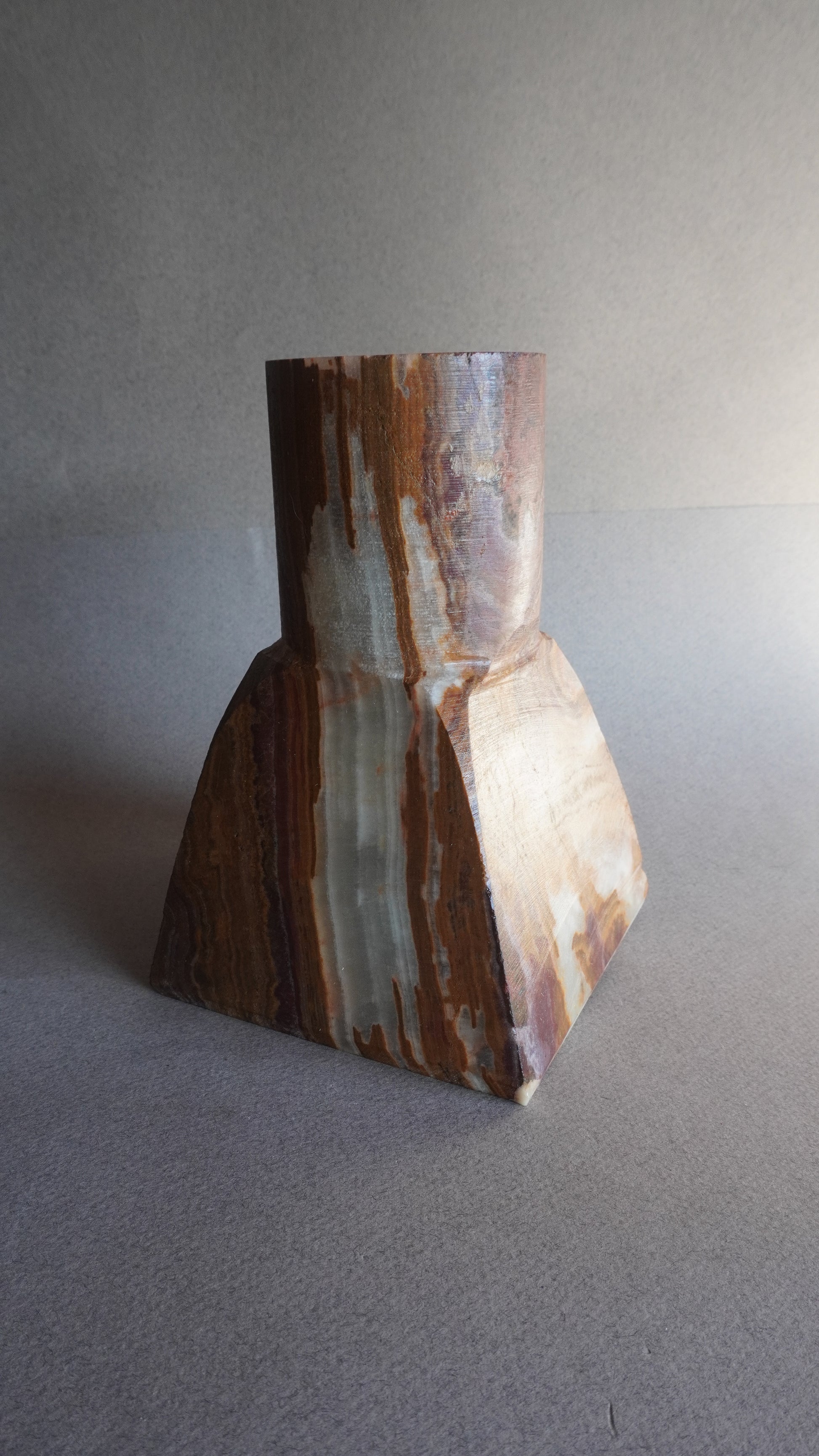 Onyx brown vase with layered structure on a gray background
