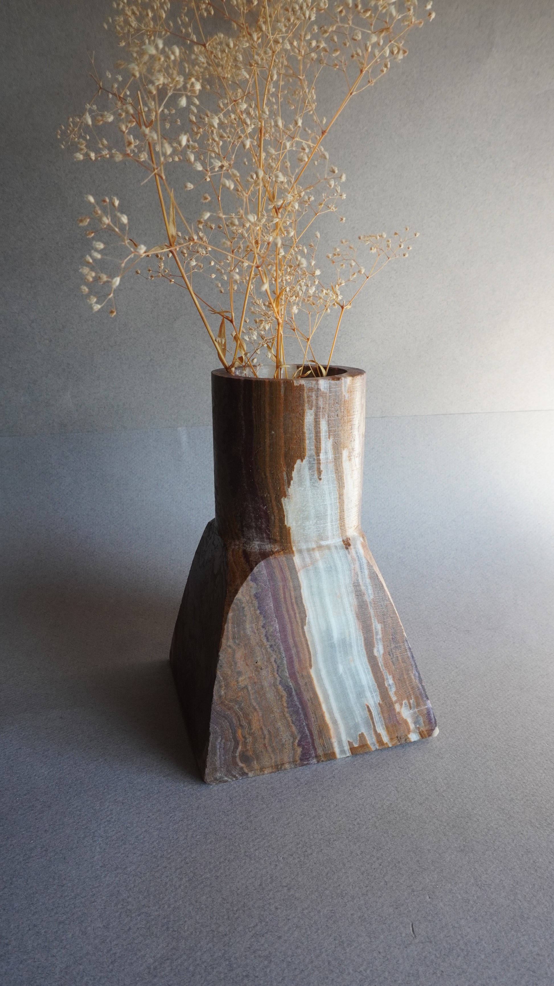 Close-up of a stone vase with a textured surface on a gray background