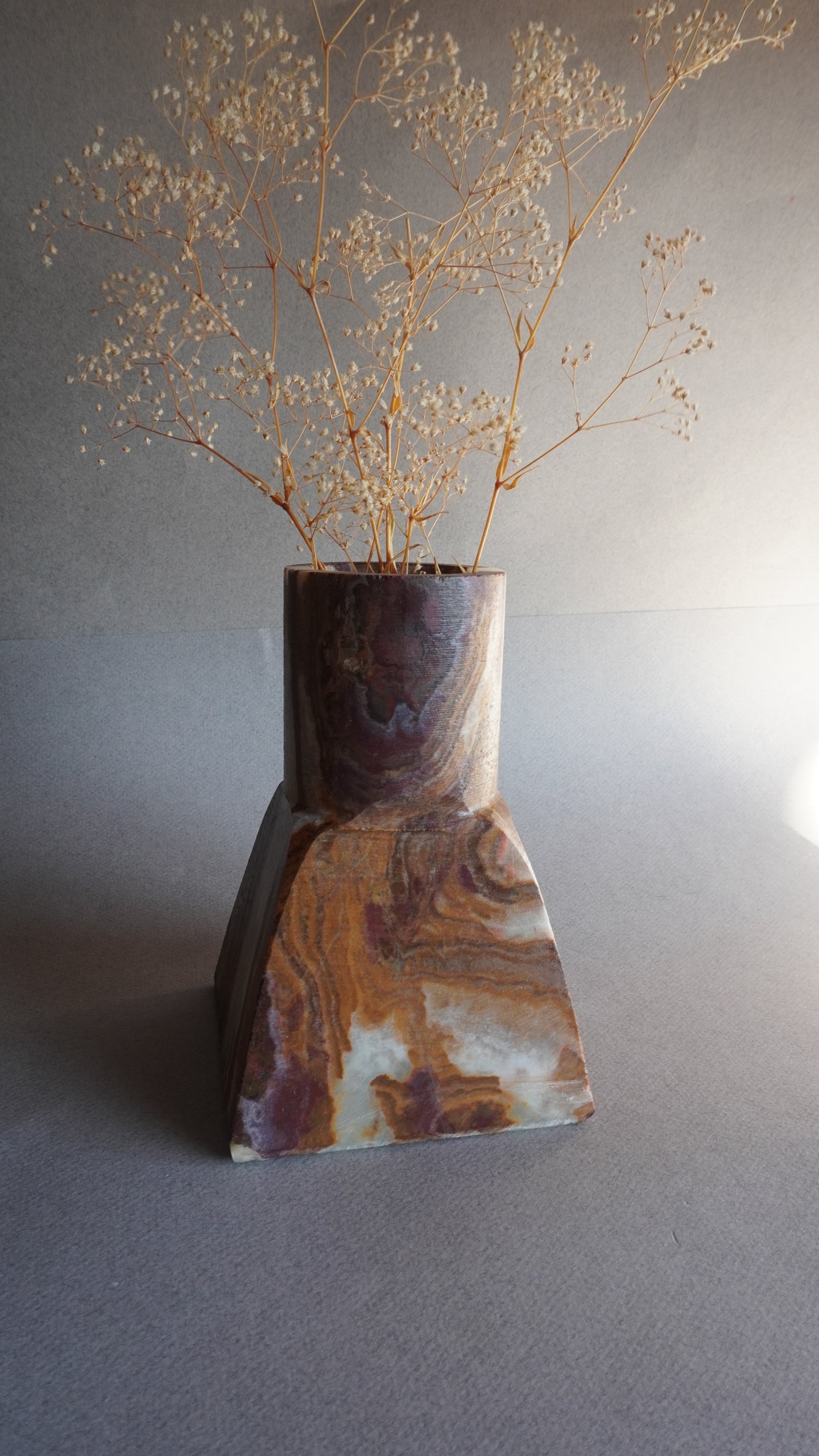 Decorative onyx vase with marbled pattern on a neutral background