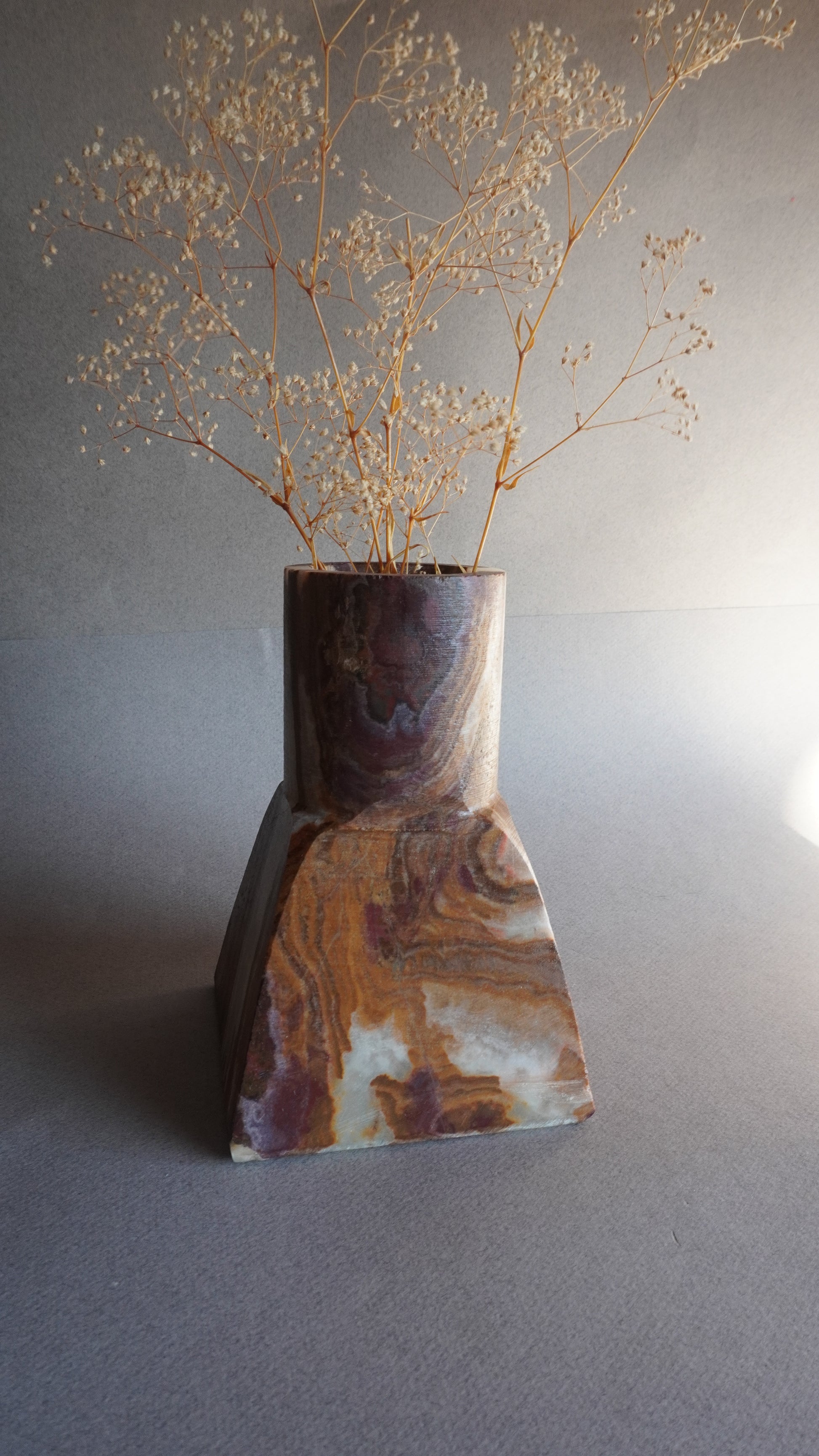 Decorative onyx vase with marbled pattern on a neutral background