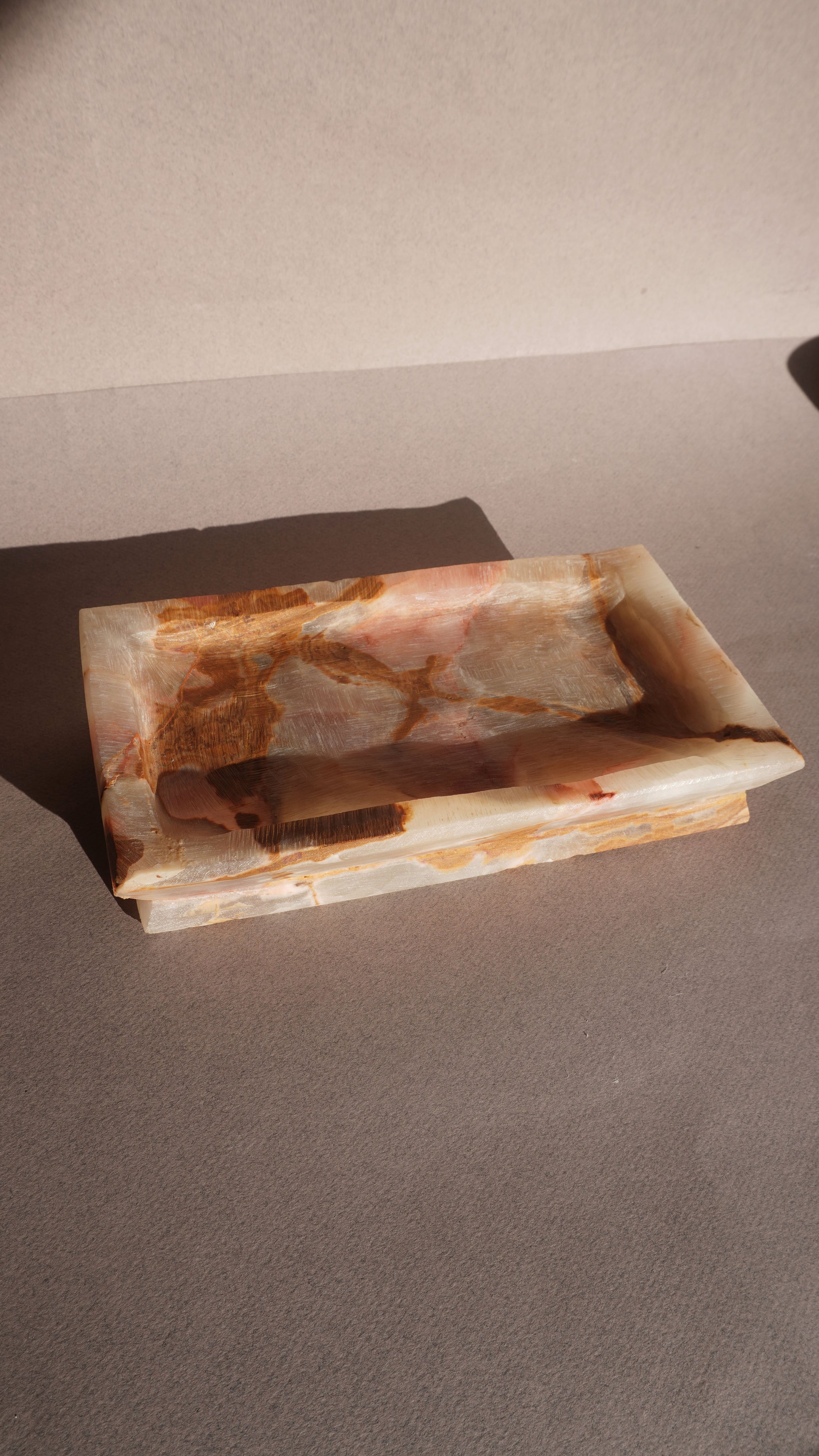 Rectangular onyx stone dish with brown and white marbled pattern on a gray surface
