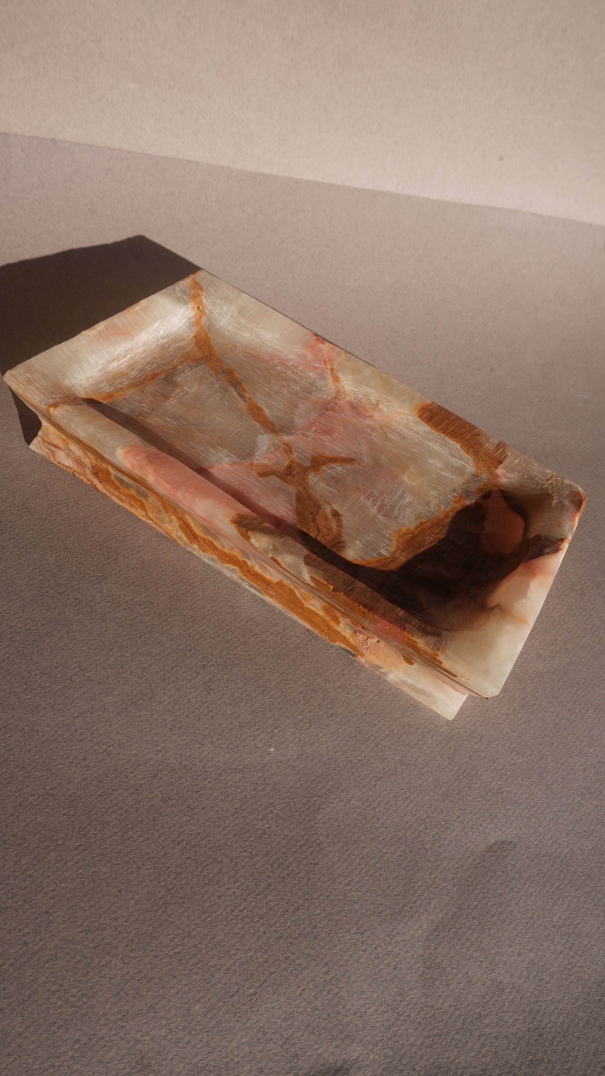Rectangular onyx stone vanity tray with a lid on a gray background