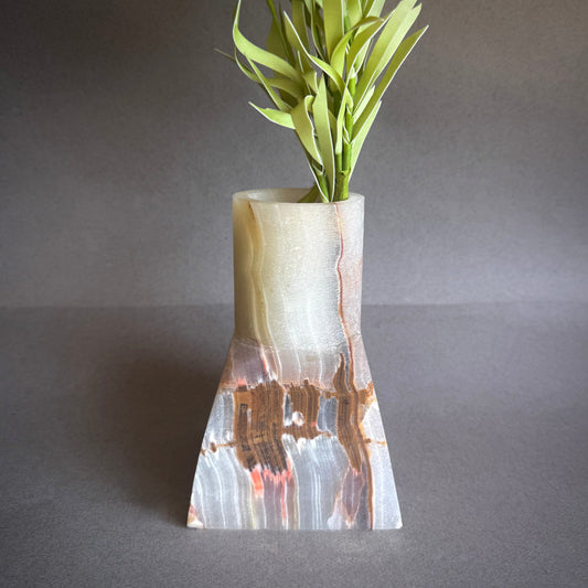 Onyx Vase with a unique design holding green plants on a gray background