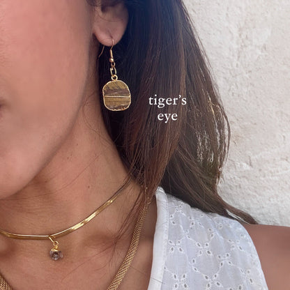 Close-up of a person wearing gold earrings and necklaces with 'tiger's eye' text.
