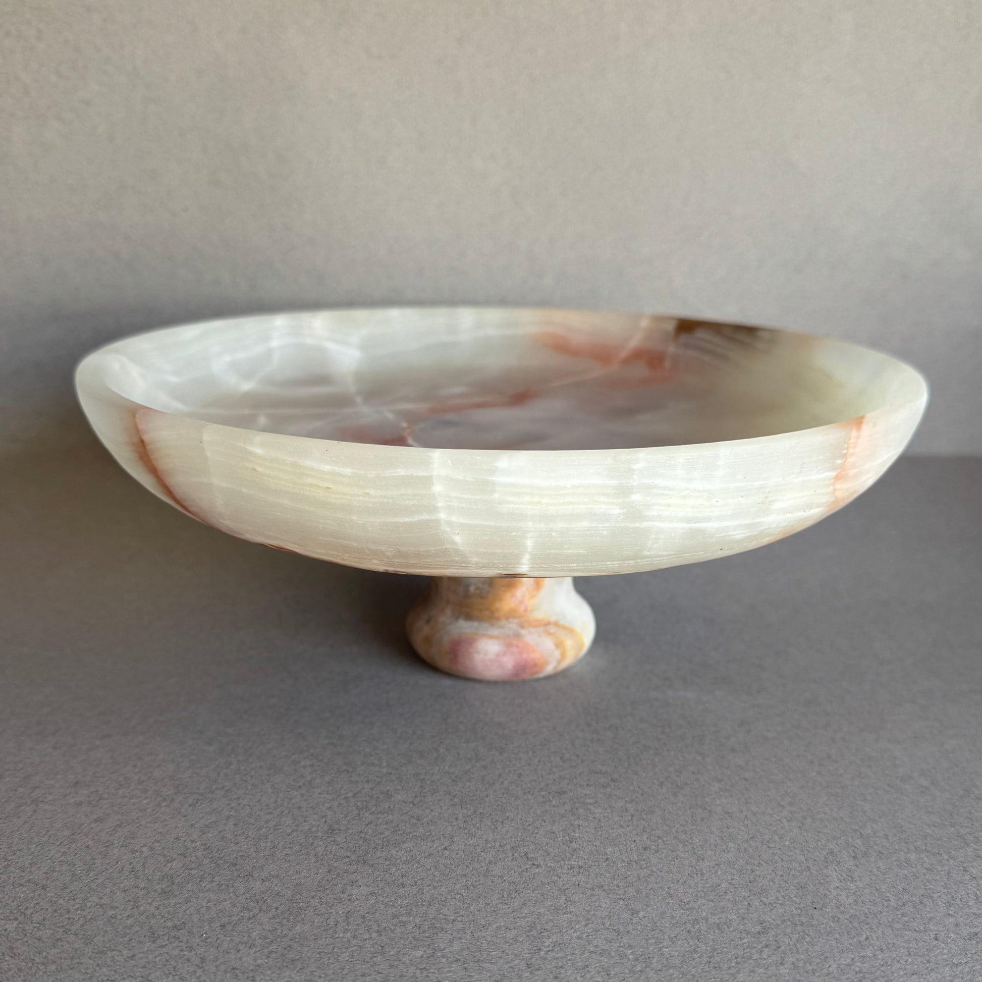 Onyx pedestal bowl glowing with natural light, showing depth and layered veining