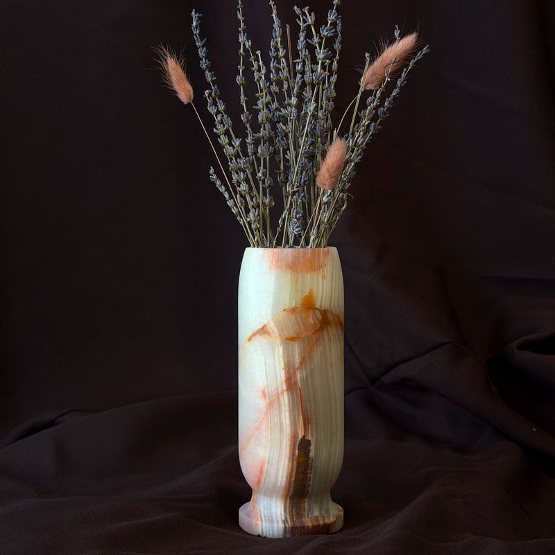 Cream and sienna onyx bud vase holding dried lavender and bunny tail grass against a dark backdrop