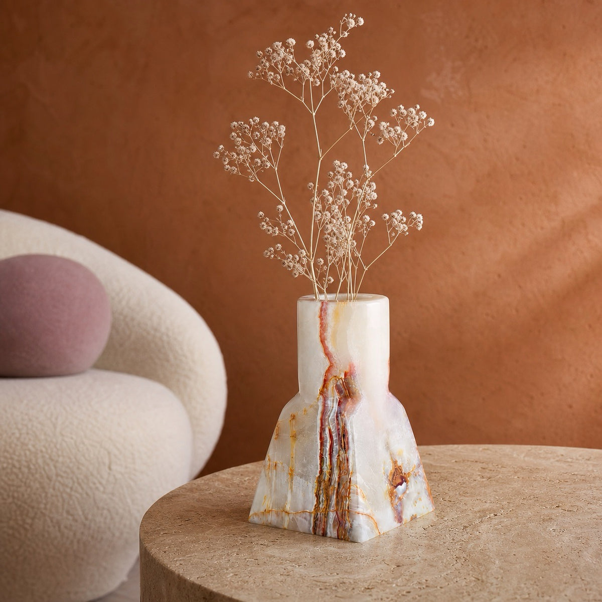 Mesa Sienna onyx vase with dried baby's breath on a round side table against a terracotta wall