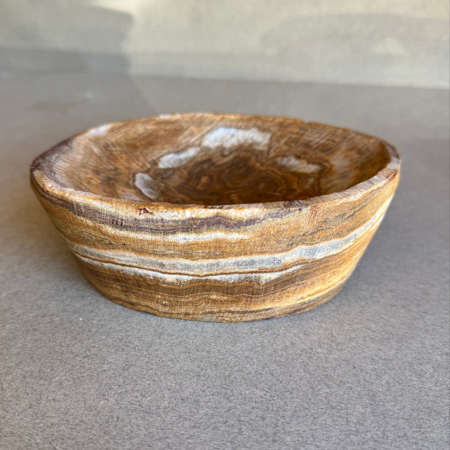 Brown stone bowl with white stripes on a gray background