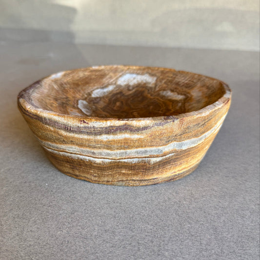 Brown stone bowl with white stripes on a gray background
