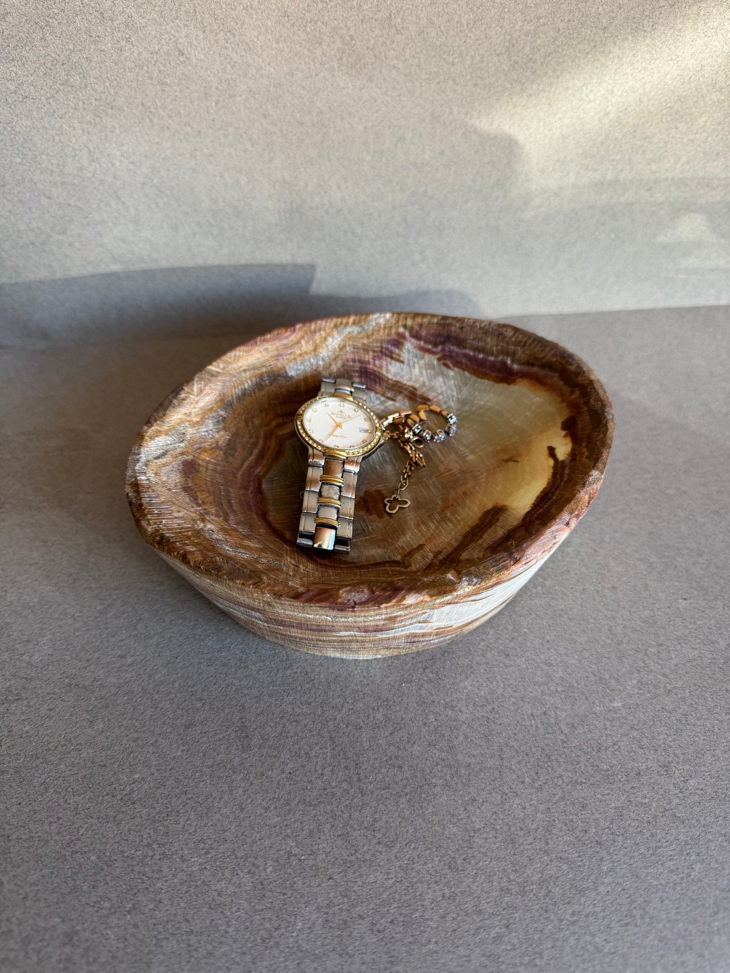 Watch and ring inside a stone bowl on a gray background