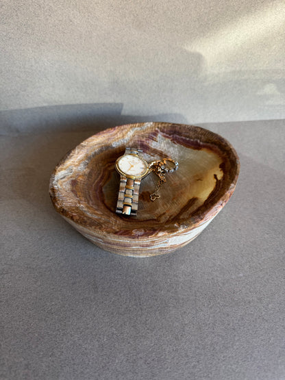 Watch and ring inside a stone bowl on a gray background