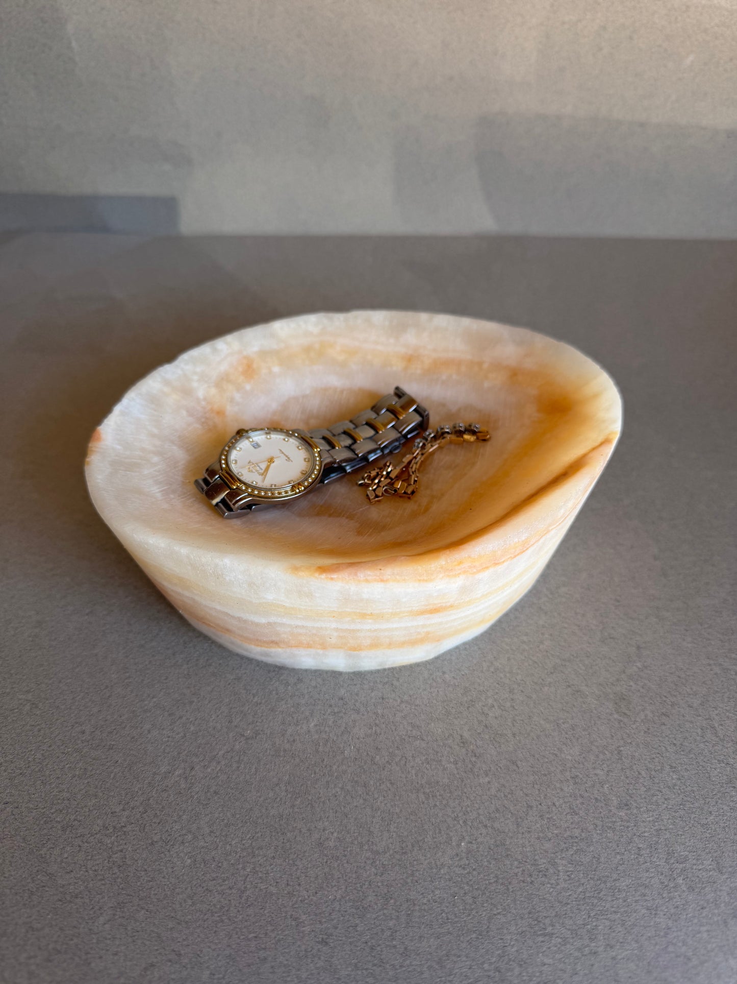 Vintage watch in a catchall onyx bowl on a gray background