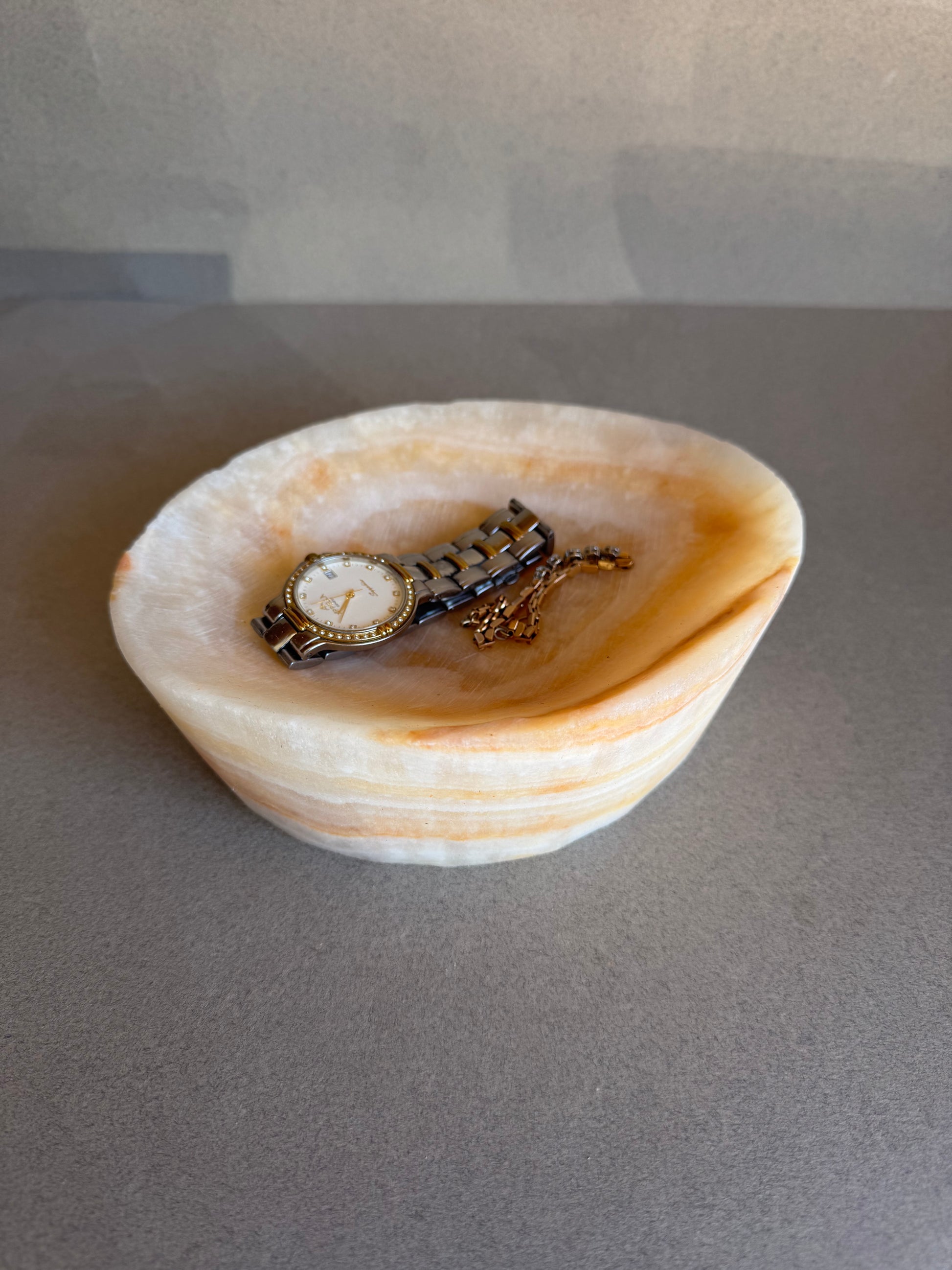 Vintage watch in a catchall onyx bowl on a gray background