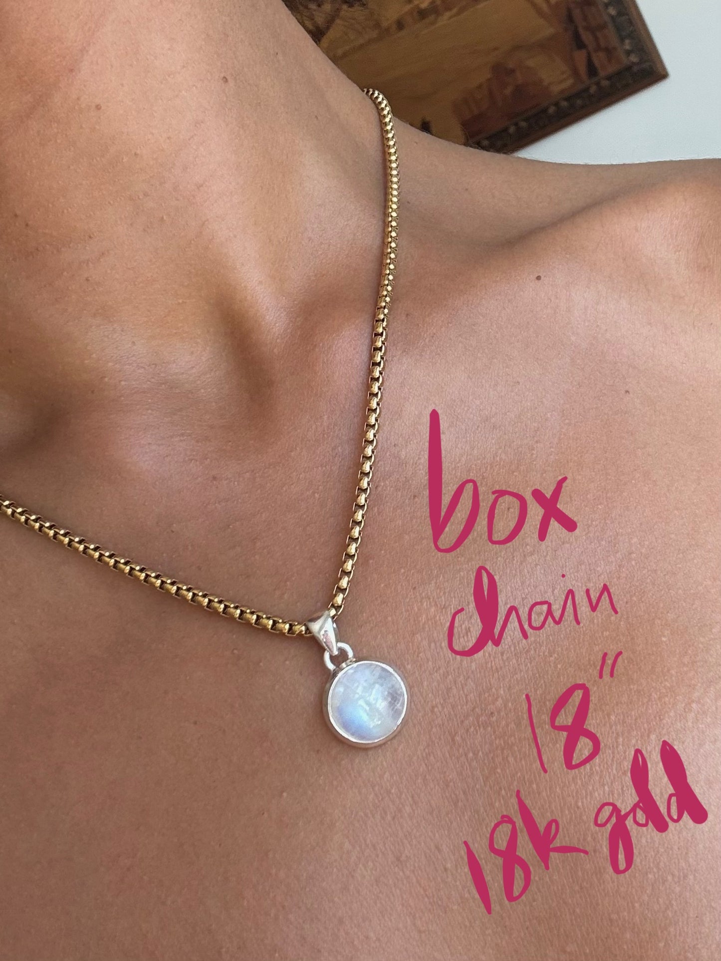 Gold box chain necklace with a silver moonstone pendant on a person's neck, with text indicating chain length and gold content.
