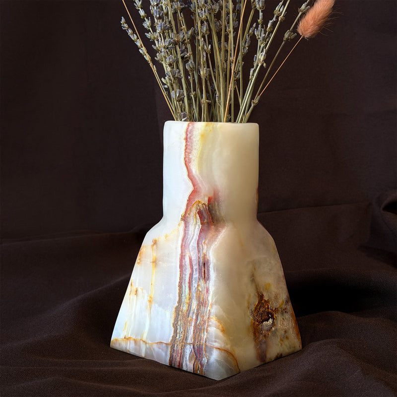 Stepped onyx bud vase, a straight neck on a tapered base, with a rust, plum and gold band running down ivory stone, holding dried lavender
