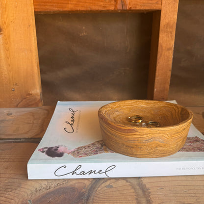 Canyon gold and rosewood onyx catchall bowl placed on a Chanel book, showcasing rich layered veining and soft matte texture

