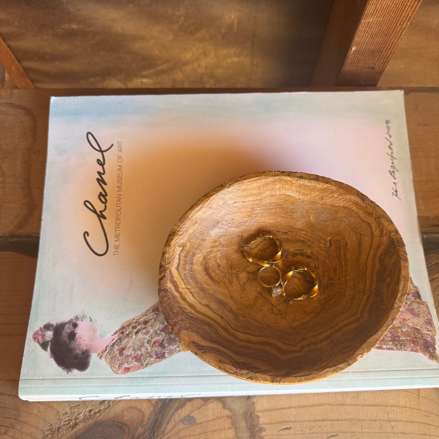 Top view of hand-carved onyx catchall bowl with warm golden and rust tones, styled with gold rings inside

