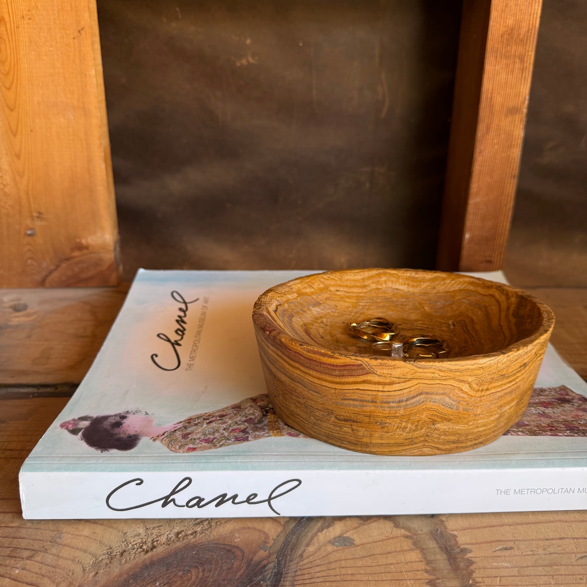 Overhead view of sculptural catchall bowl resting on a Chanel art book, styled in warm natural light


