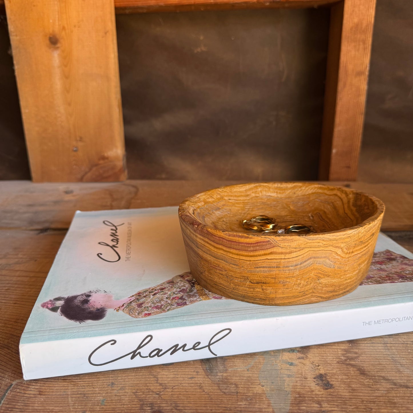 Onyx bowl styled with rings inside, sitting on a wooden surface and fashion book


